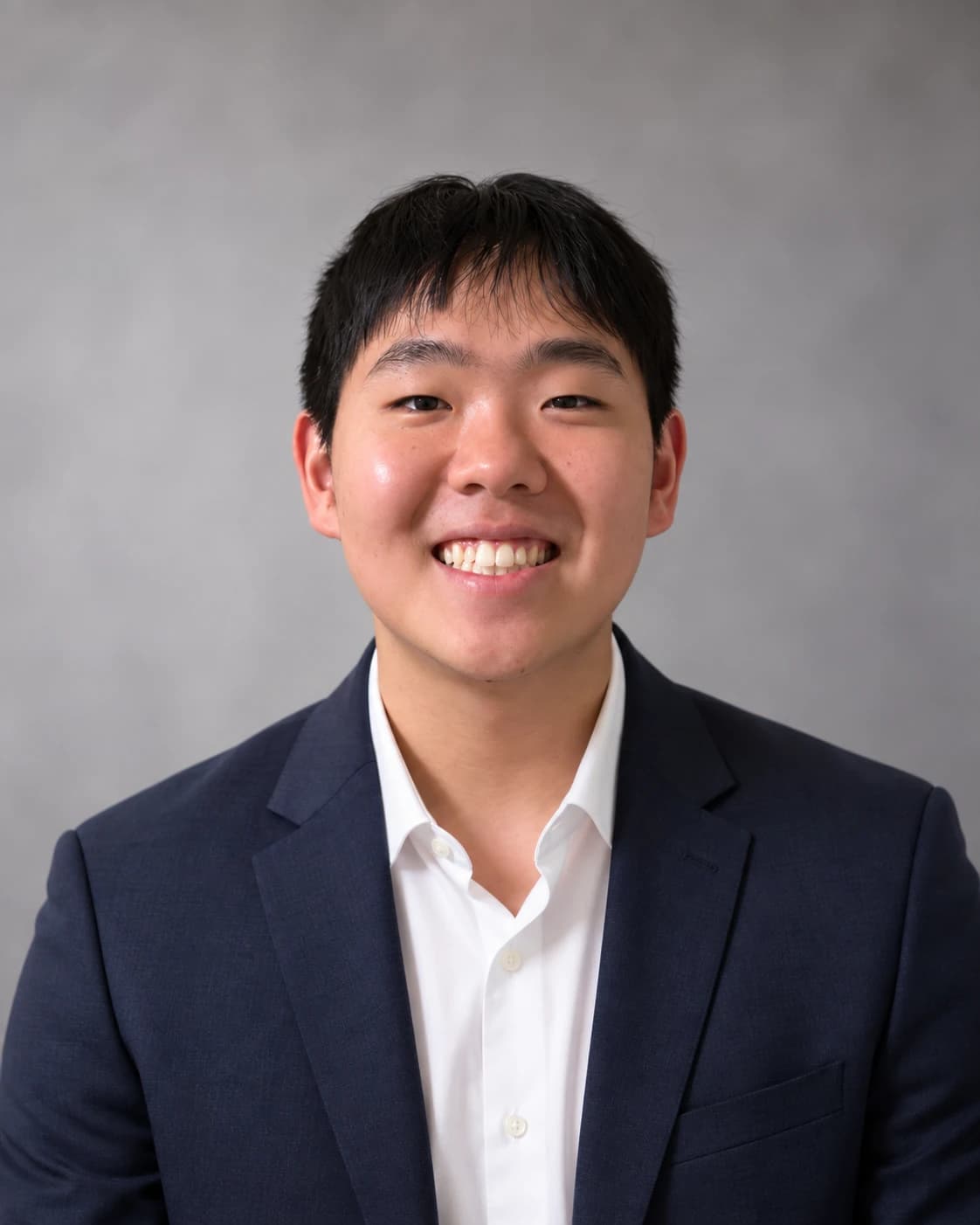 Portrait of Tae Bark in a navy blazer against a grey backdrop.
